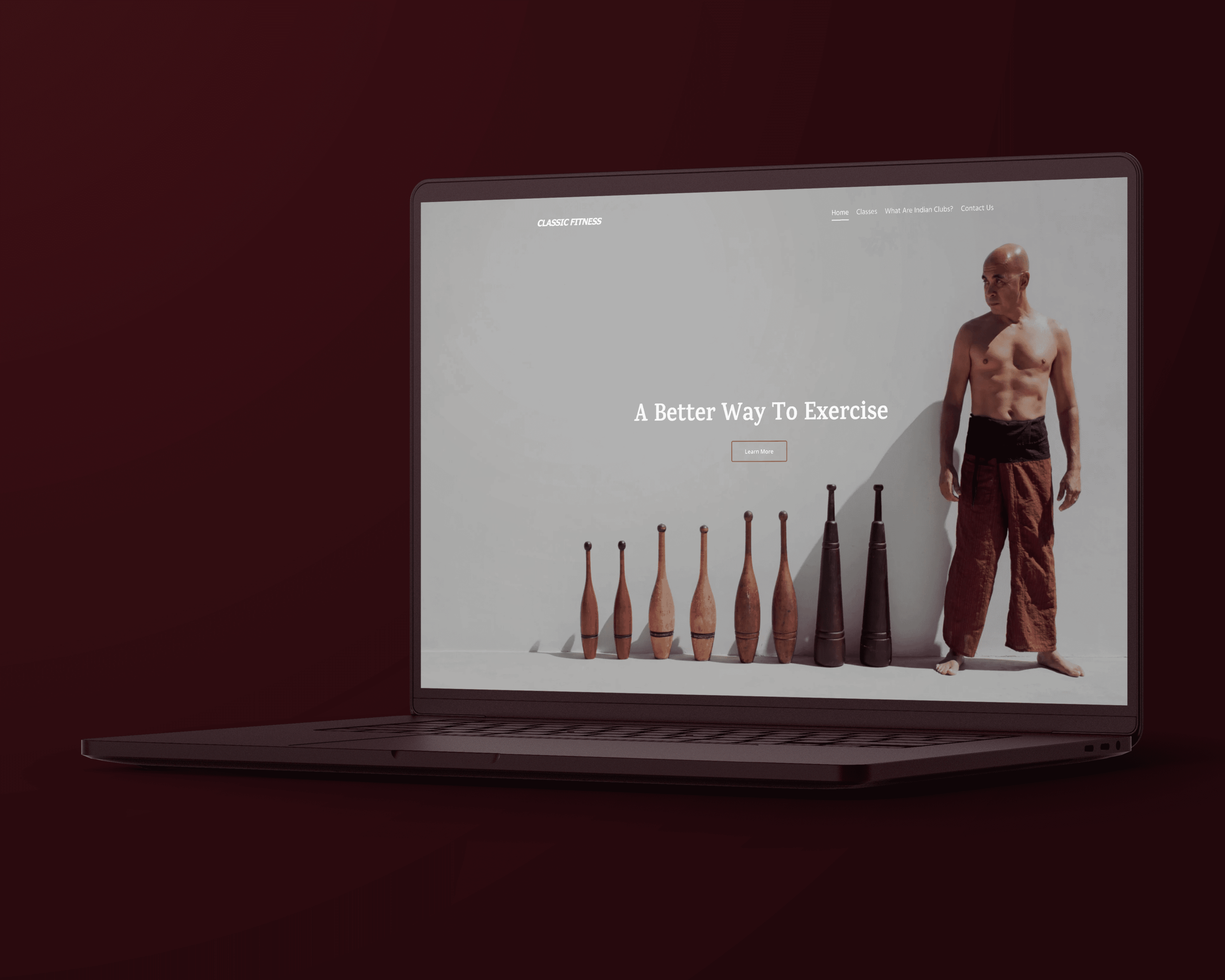 Laptop displaying fitness website design featuring a man with exercise clubs and text "A Better Way to Exercise."
