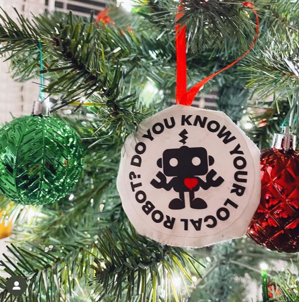 Christmas tree with ornaments and a "Do You Know Your Local Robot?" sticker featuring a robot.