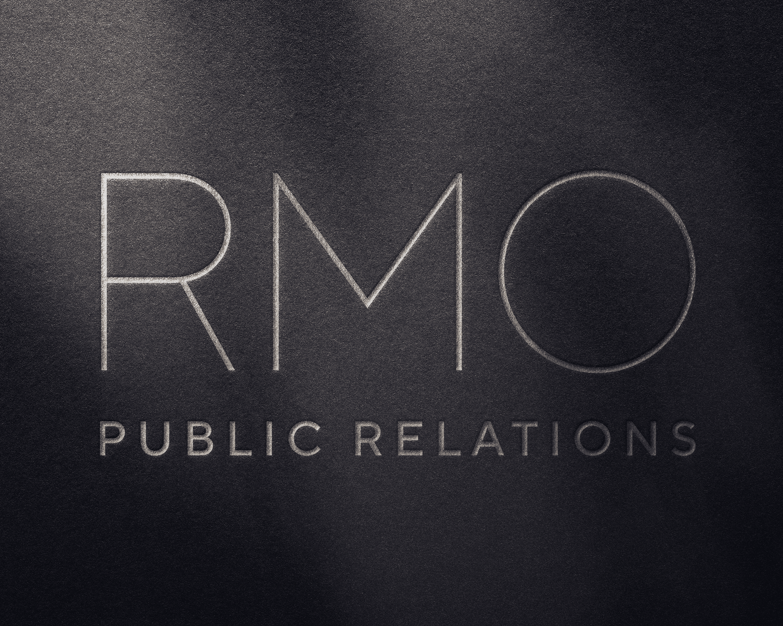 Custom embossed RMO Public Relations logo on a dark, textured background.