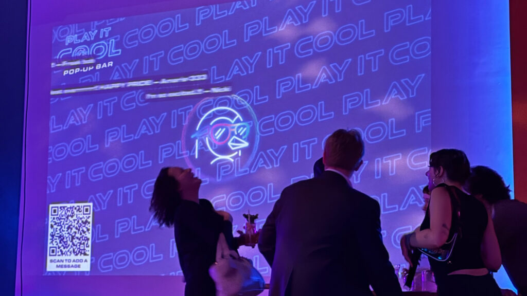 Live audio visualizer at the Play It Cool pop-up bar, featuring neon graphics and a QR code for messages.