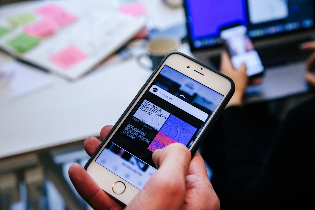 A person holds a smartphone displaying a colorful design, while another phone is visible in the background.