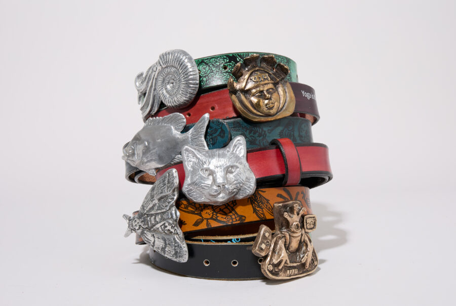 A stack of colorful belts featuring various animal-shaped metal buckles.