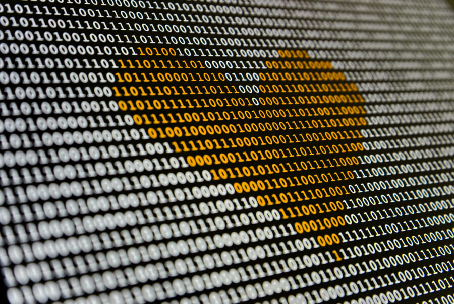 Binary code displayed on a screen, with a heart shape formed by orange digits.