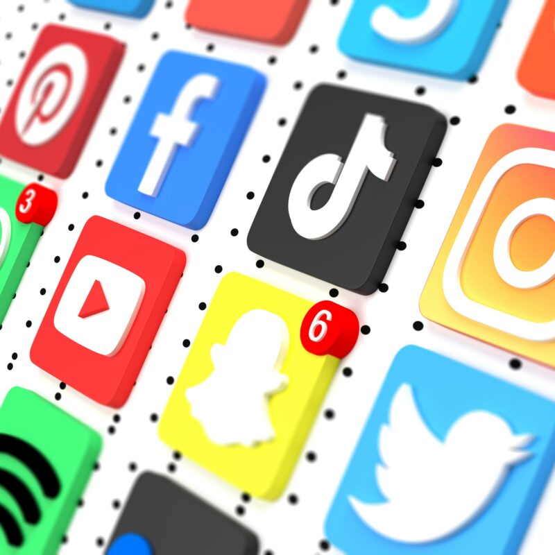Colorful social media app icons arranged on a dotted background, with notification badges visible.